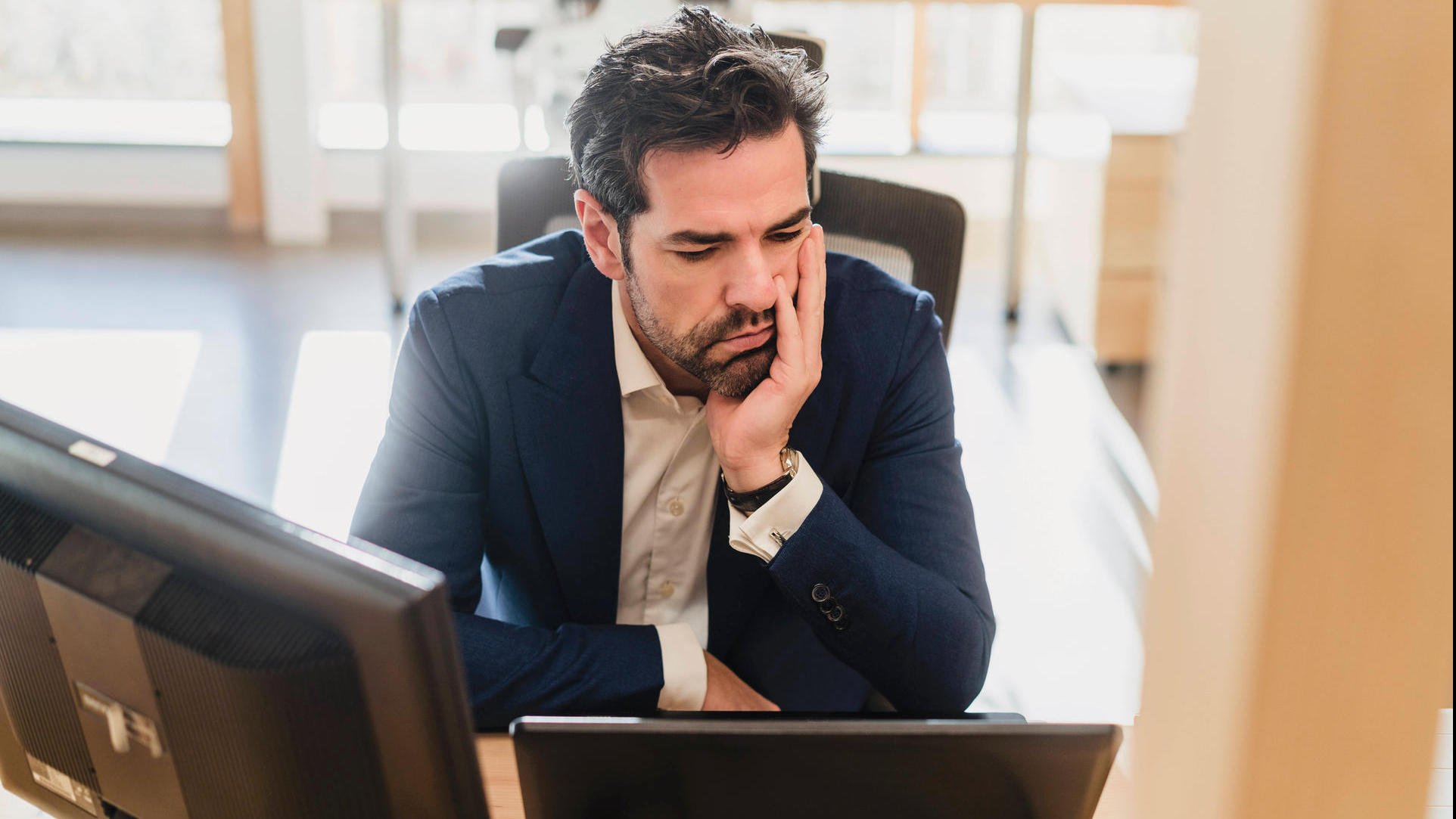 Frustrated businessman sitting at desk in office model released Symbolfoto property released PUBLICATIONxINxGERxSUIxAUTx